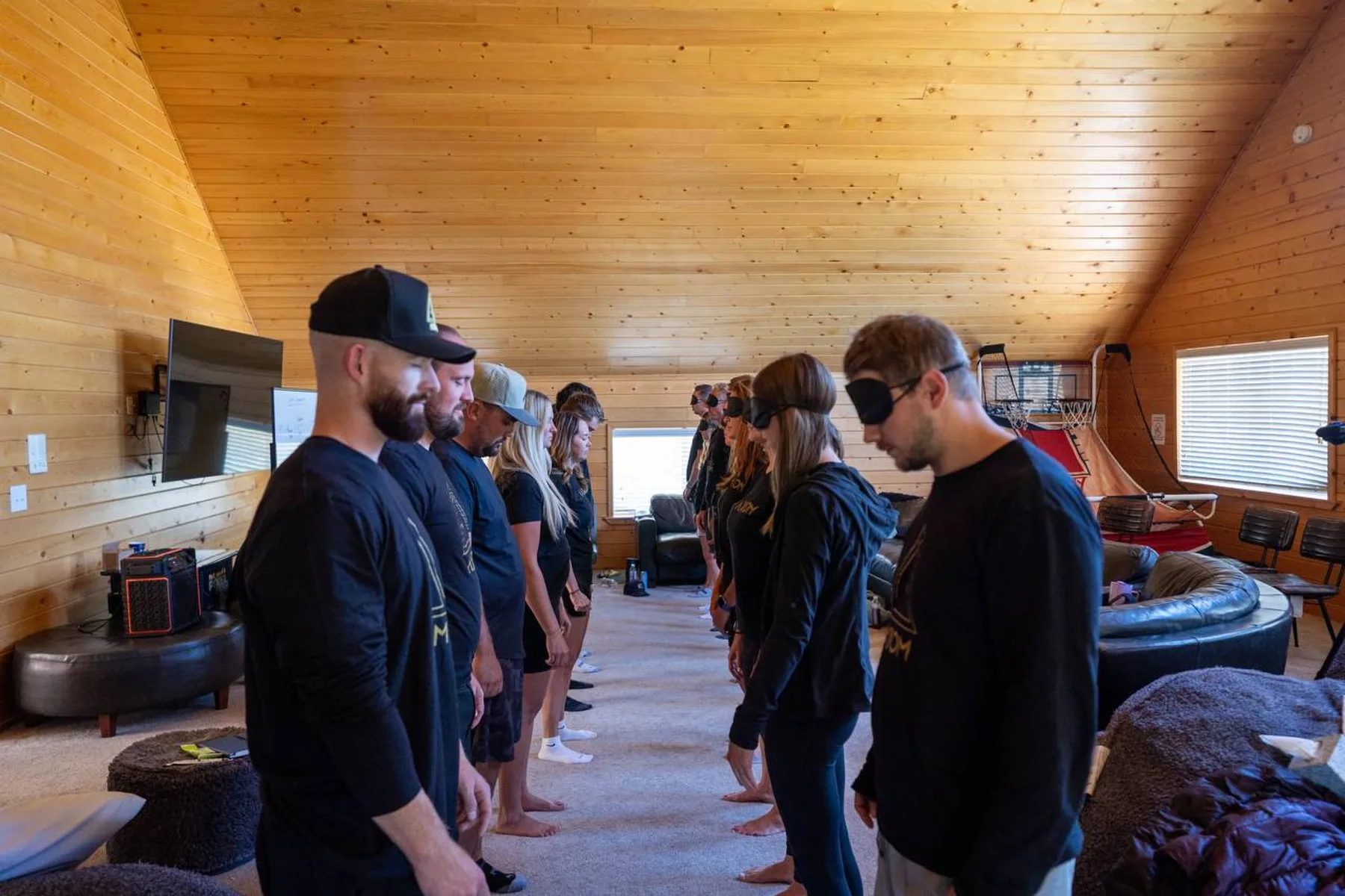 A line of workshop participants in blindfolds, hands on each other's shoulders, during one of Zack Blakeney's retreats.