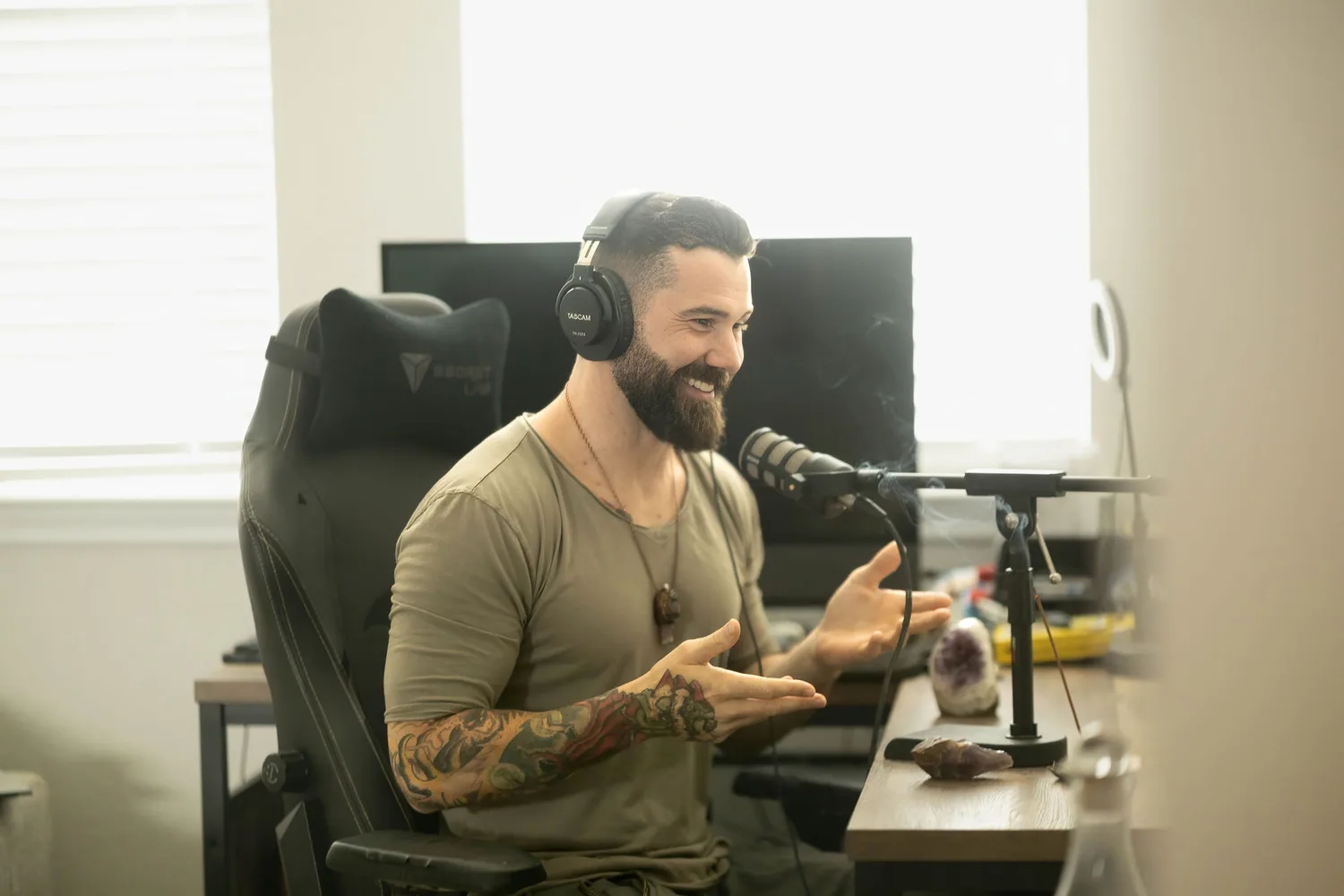 Zack Blakeney speaking into a studio microphone with headphones on, mid-gesture.